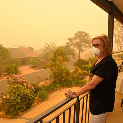 Woman standing on her porch looking over her suburb in a smoke haze